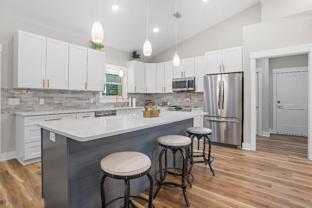 3112 Evans Ave, Navarre, FL 32566 - kitchen with appliances with stainless steel finishes, a kitchen breakfast bar, white cabinets, light countertops, and lofted ceiling