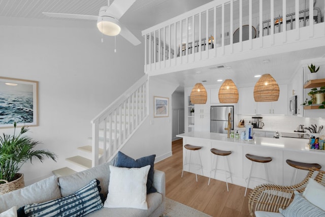 4984 W County Highway 30a Unit 5B, Santa Rosa Beach, FL 32459 - living room with light wood-style floors, stairway, a towering ceiling, and a ceiling fan