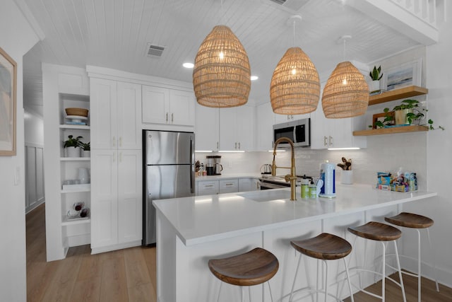 4984 W County Highway 30a Unit 5B, Santa Rosa Beach, FL 32459 - kitchen featuring stainless steel appliances, open shelves, light wood-type flooring, a peninsula, and light countertops