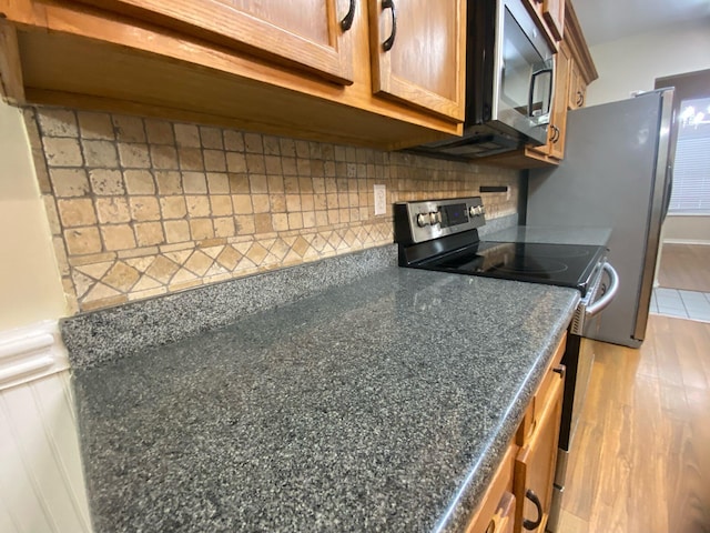 64 Hampton Cir, Niceville, FL 32578 - kitchen featuring stainless steel appliances, dark countertops, decorative backsplash, and wood finished floors