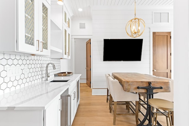 17 Palm Court Ln, Inlet Beach, FL 32461 - kitchen featuring light wood-type flooring, a chandelier, white cabinetry, pendant lighting, and glass insert cabinets