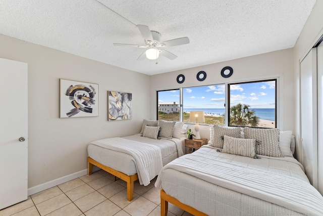 23223 Front Beach Rd # 112, Panama City Beach, FL 32413 - bedroom with light tile patterned floors, a ceiling fan, a closet, a water view, and a textured ceiling