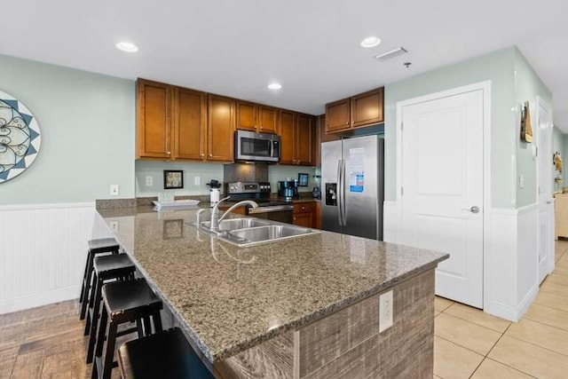 16701 Front Beach Rd Unit 1807, Panama City Beach, FL 32413 - kitchen featuring appliances with stainless steel finishes, a peninsula, a breakfast bar area, brown cabinetry, and wainscoting
