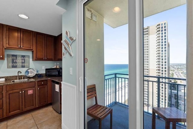 16701 Front Beach Rd Unit 1807, Panama City Beach, FL 32413 - kitchen with stainless steel dishwasher, light tile patterned flooring, dark stone counters, a water view, and brown cabinetry