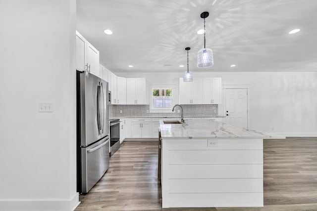 2672 Chat Holley Rd, Santa Rosa Beach, FL 32459 - kitchen featuring appliances with stainless steel finishes, wood finished floors, a center island with sink, white cabinets, and light stone countertops