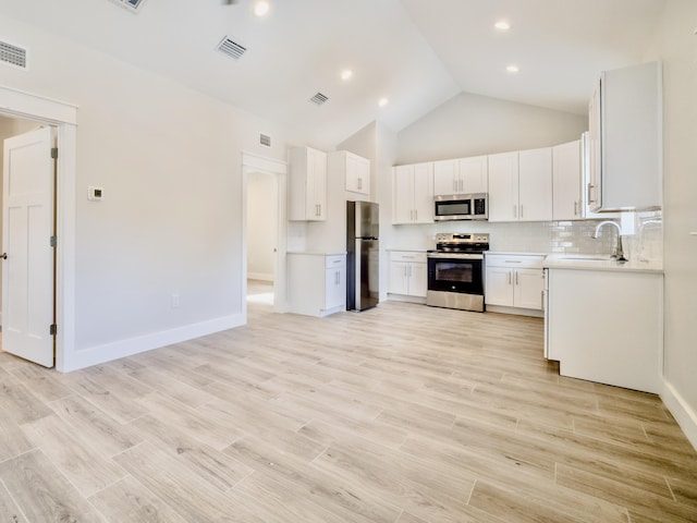 116 E Georgie Pt, Washington, FL 32459 - kitchen featuring appliances with stainless steel finishes, decorative backsplash, light countertops, white cabinets, and high vaulted ceiling
