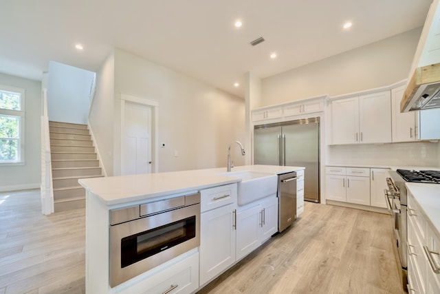 116 E Georgie Pt, Washington, FL 32459 - kitchen with high quality appliances, white cabinetry, light wood finished floors, and recessed lighting