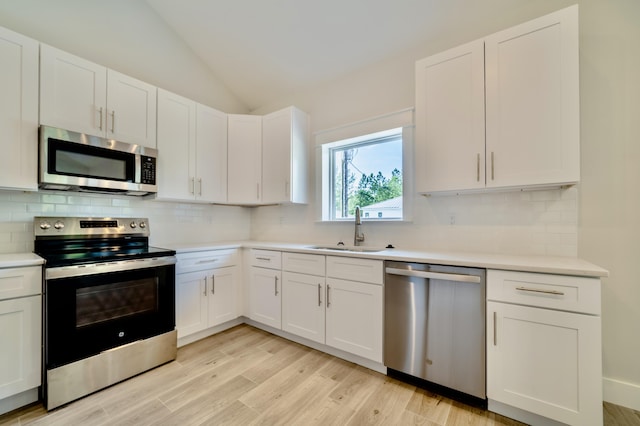 116 E Georgie Pt, Washington, FL 32459 - kitchen with stainless steel appliances, lofted ceiling, light countertops, white cabinets, and tasteful backsplash