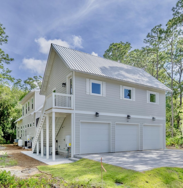 116 E Georgie Pt, Washington, FL 32459 - view of home's exterior with an attached garage, concrete driveway, stairs, a metal roof, and a standing seam roof