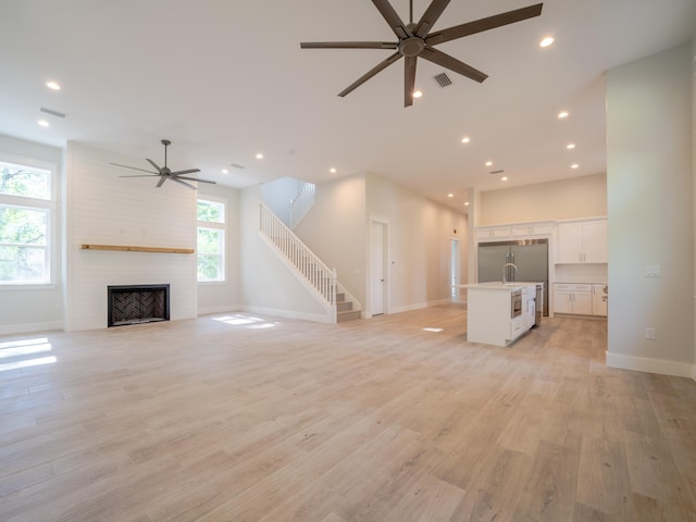 116 E Georgie Pt, Washington, FL 32459 - unfurnished living room with ceiling fan, recessed lighting, light wood-style floors, a large fireplace, and stairs