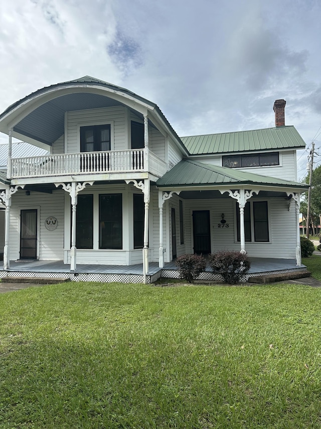 273 E Live Oak Ave, Defuniak Springs, FL 32435 - back of property with covered porch, a balcony, a lawn, and a chimney