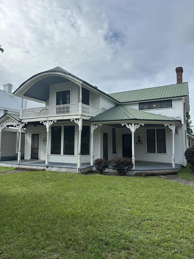 273 E Live Oak Ave, Defuniak Springs, FL 32435 - back of house featuring covered porch, a balcony, a chimney, a yard, and a metal roof