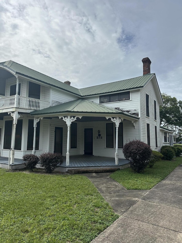 273 E Live Oak Ave, Defuniak Springs, FL 32435 - view of front of house featuring a chimney, covered porch, a front yard, and a metal roof