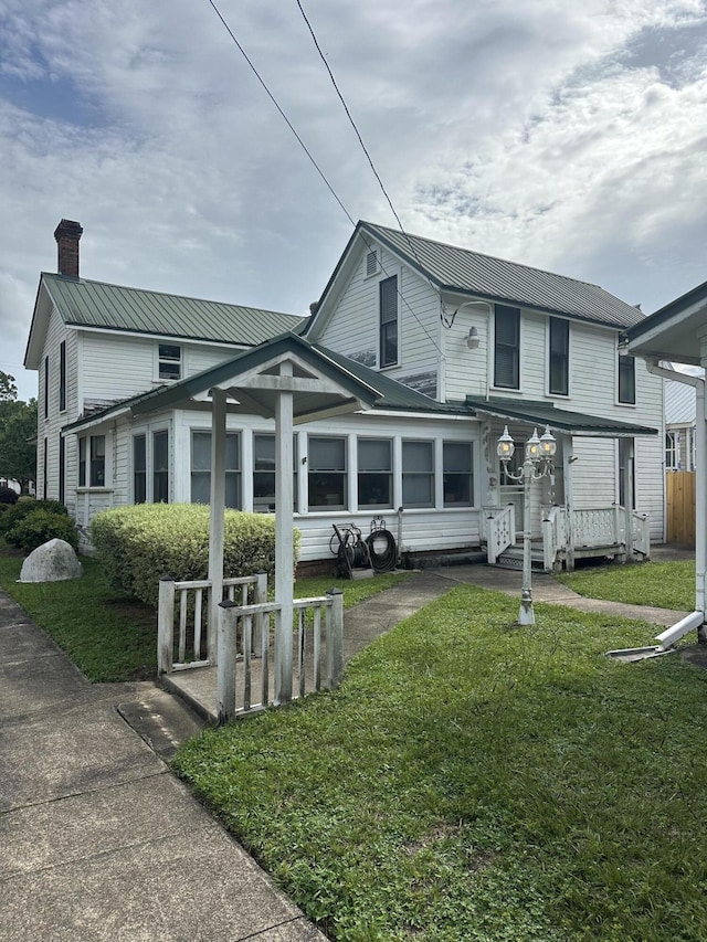 273 E Live Oak Ave, Defuniak Springs, FL 32435 - traditional home featuring a chimney, a front lawn, and a metal roof
