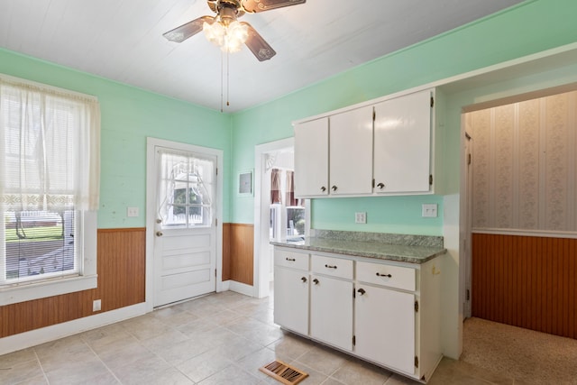 273 E Live Oak Ave, Defuniak Springs, FL 32435 - kitchen with wainscoting, ceiling fan, white cabinets, wood walls, and light countertops