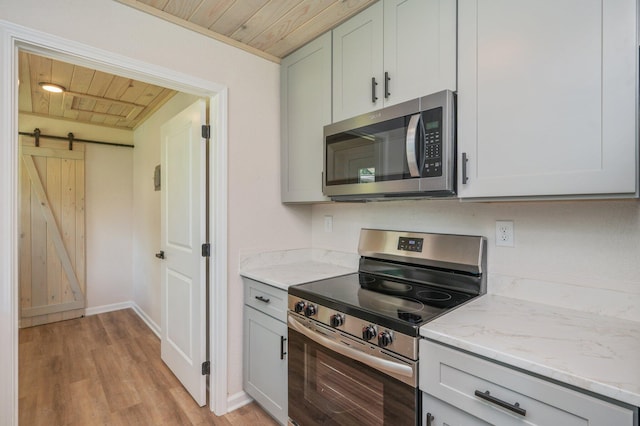 3375 Mclain Dr, Crestview, FL 32539 - kitchen with appliances with stainless steel finishes, wood ceiling, a barn door, light stone countertops, and light wood-style floors