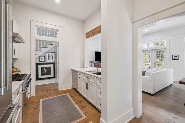 58 Pine Needle Way, Santa Rosa Beach, FL 32459 - kitchen with premium appliances, white cabinetry, light wood finished floors, recessed lighting, and extractor fan