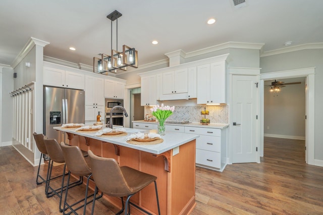 2580 Taylor Rd, Crestview, FL 32536 - kitchen with stainless steel appliances, crown molding, light countertops, white cabinets, and an island with sink