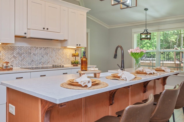 2580 Taylor Rd, Crestview, FL 32536 - kitchen with under cabinet range hood, black electric cooktop, backsplash, ornamental molding, and white cabinetry