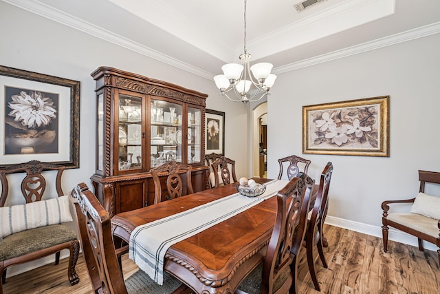 419 Symphony Way, Freeport, FL 32439 - dining room with arched walkways, a chandelier, wood finished floors, a tray ceiling, and crown molding