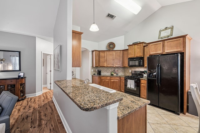 419 Symphony Way, Freeport, FL 32439 - kitchen featuring black appliances, brown cabinetry, a peninsula, backsplash, and arched walkways
