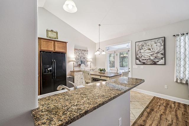 419 Symphony Way, Freeport, FL 32439 - kitchen featuring black fridge with ice dispenser, brown cabinetry, decorative light fixtures, dark stone countertops, and high vaulted ceiling