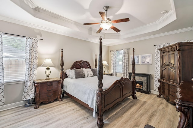 419 Symphony Way, Freeport, FL 32439 - bedroom featuring a tray ceiling, light wood-style floors, crown molding, ceiling fan, and a stone fireplace