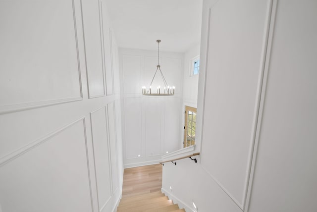 7215 Sunset Ave, Panama City Beach, FL 32408 - hall featuring a decorative wall, a chandelier, and light wood-style flooring