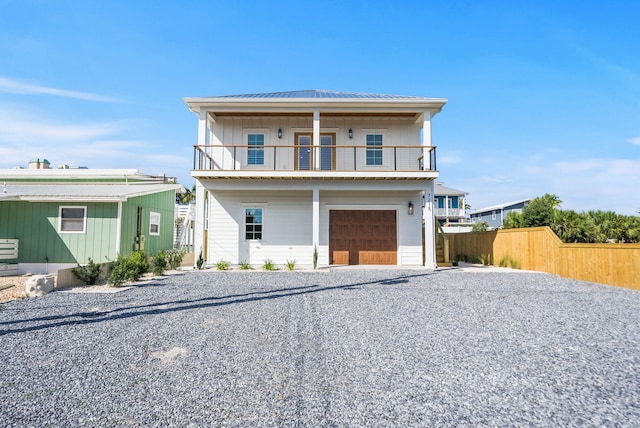 7215 Sunset Ave, Panama City Beach, FL 32408 - view of front of house featuring a balcony, a garage, gravel driveway, a metal roof, and a standing seam roof