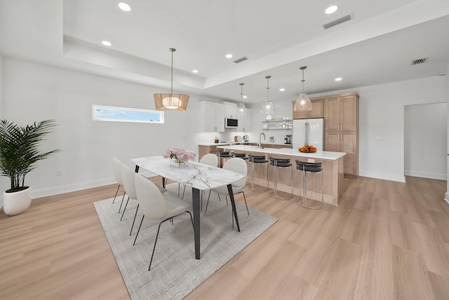 7215 Sunset Ave, Panama City Beach, FL 32408 - dining room with light wood-style floors, a raised ceiling, and recessed lighting