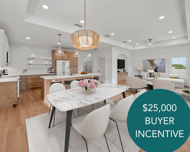 7215 Sunset Ave, Panama City Beach, FL 32408 - dining area with a tray ceiling, light wood-type flooring, ceiling fan, arched walkways, and recessed lighting