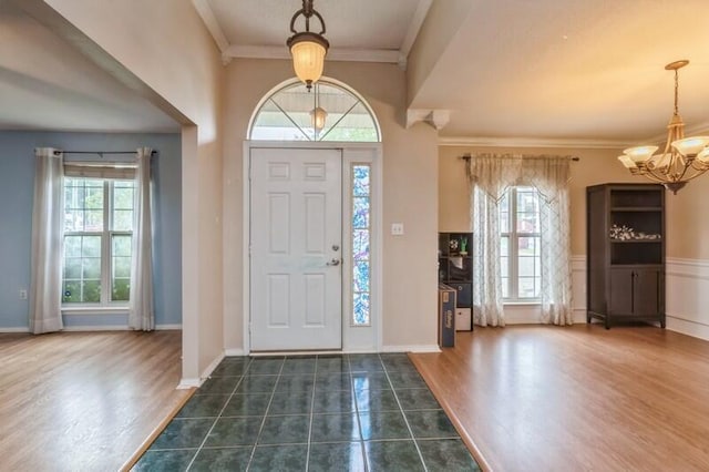 527 Tom Sawyer Ln, Crestview, FL 32536 - foyer with healthy amount of natural light, a chandelier, crown molding, dark tile patterned floors, and a wainscoted wall
