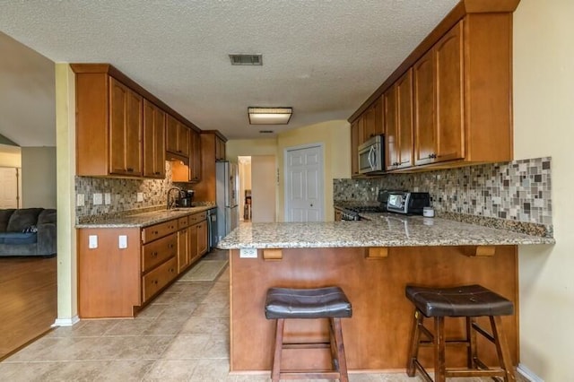 527 Tom Sawyer Ln, Crestview, FL 32536 - kitchen featuring stainless steel appliances, light stone counters, tasteful backsplash, a peninsula, and a textured ceiling
