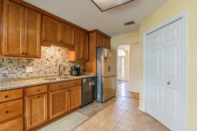 527 Tom Sawyer Ln, Crestview, FL 32536 - kitchen featuring freestanding refrigerator, dishwasher, brown cabinets, tasteful backsplash, and light stone countertops