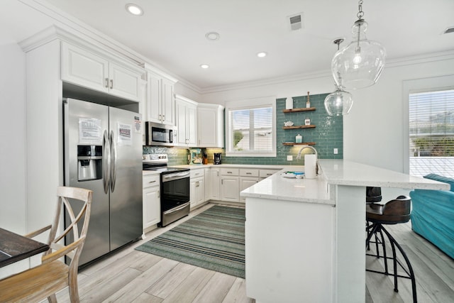 30 Los Angeles St, Miramar Beach, FL 32550 - kitchen featuring stainless steel appliances, a breakfast bar area, a peninsula, light wood finished floors, and tasteful backsplash