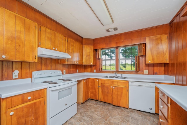 942 Varnum Rd, Laurel Hill, FL 32567 - kitchen featuring white appliances, under cabinet range hood, light countertops, wood walls, and brown cabinets