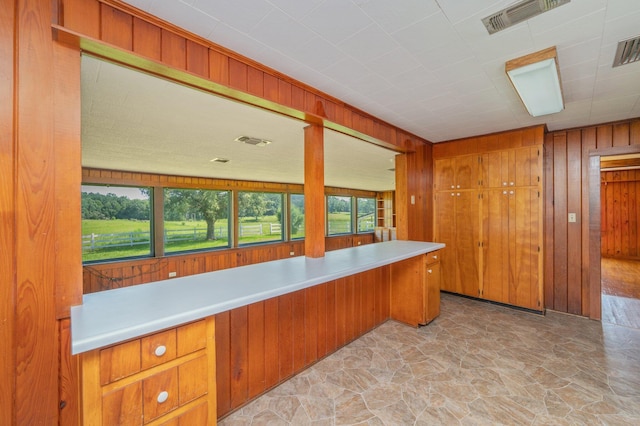 942 Varnum Rd, Laurel Hill, FL 32567 - kitchen with wood walls, stone floors, light countertops, and brown cabinets