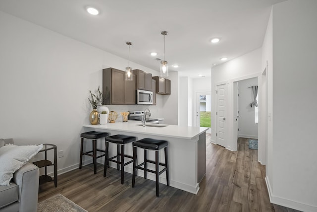 5862 Tyndall Pl, Panama City, FL 32404 - kitchen featuring stainless steel microwave, a peninsula, dark wood-type flooring, light countertops, and a breakfast bar
