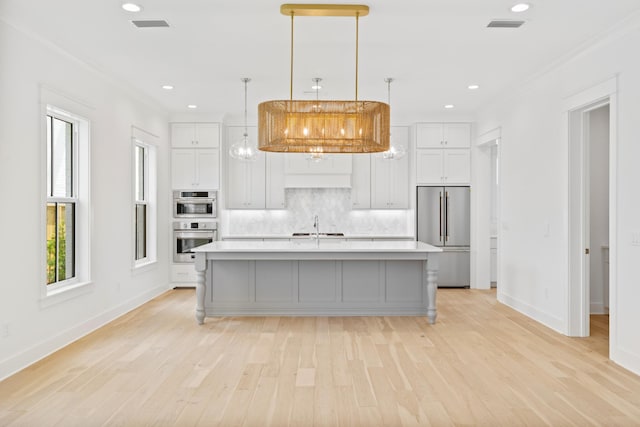 368 Ridgewalk Cir Lot 44B, Santa Rosa Beach, FL 32459 - kitchen with appliances with stainless steel finishes, light countertops, decorative backsplash, light wood-style floors, and a center island with sink