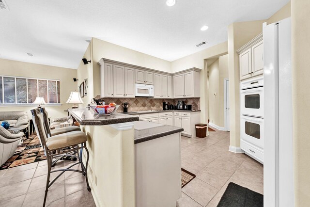 423 Maritime Ct, Destin, FL 32541 - kitchen with white appliances, dark countertops, tasteful backsplash, a breakfast bar, and a peninsula