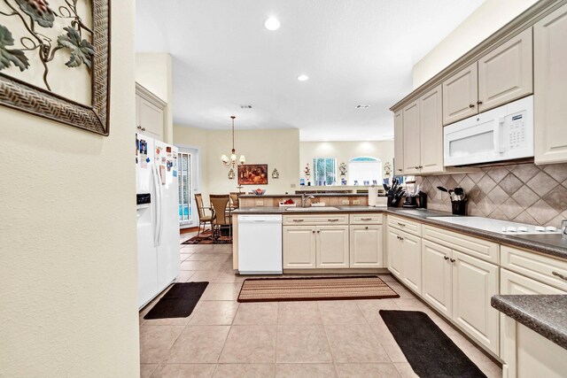 423 Maritime Ct, Destin, FL 32541 - kitchen with white appliances, a peninsula, a chandelier, dark countertops, and backsplash