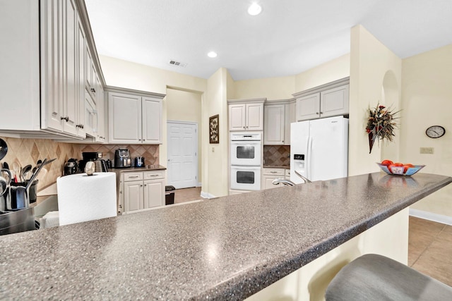 423 Maritime Ct, Destin, FL 32541 - kitchen with white appliances, a breakfast bar, dark countertops, a peninsula, and recessed lighting