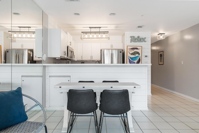 2606 Scenic Gulf Dr Unit 4206, Miramar Beach, FL 32550 - kitchen featuring appliances with stainless steel finishes, a peninsula, light tile patterned floors, and a kitchen breakfast bar