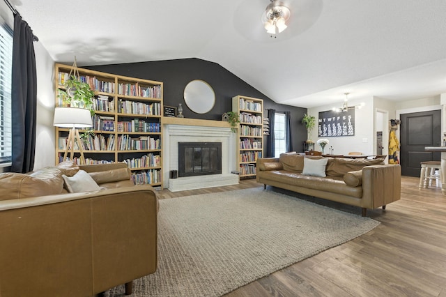 3774 Laird Rd, Crestview, FL 32539 - living room with wood finished floors, vaulted ceiling, a glass covered fireplace, and a chandelier