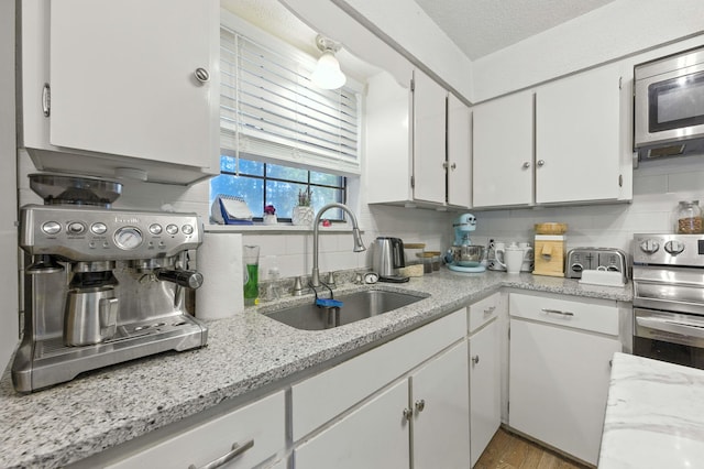 3774 Laird Rd, Crestview, FL 32539 - kitchen with appliances with stainless steel finishes, white cabinetry, decorative backsplash, wood finished floors, and light stone counters