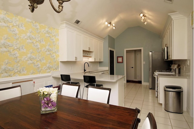 1262 Whitewood Way, Niceville, FL 32578 - kitchen with stainless steel microwave, a wainscoted wall, light tile patterned flooring, light countertops, and a peninsula