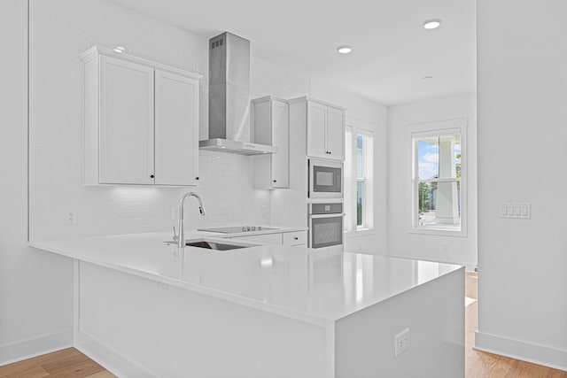 128 Ravine Rd, Watersound, FL 32461 - kitchen with stainless steel oven, wall chimney range hood, light countertops, light wood-type flooring, and built in microwave