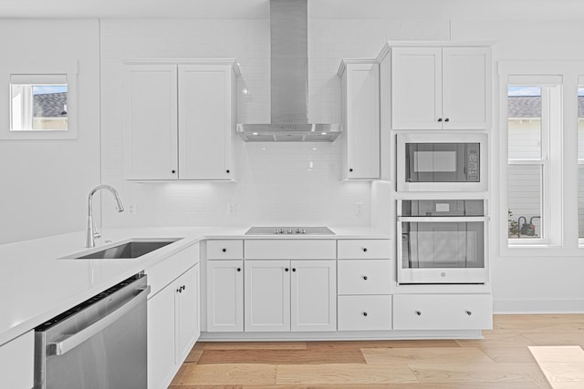 128 Ravine Rd, Watersound, FL 32461 - kitchen featuring black appliances, wall chimney exhaust hood, light countertops, and white cabinetry