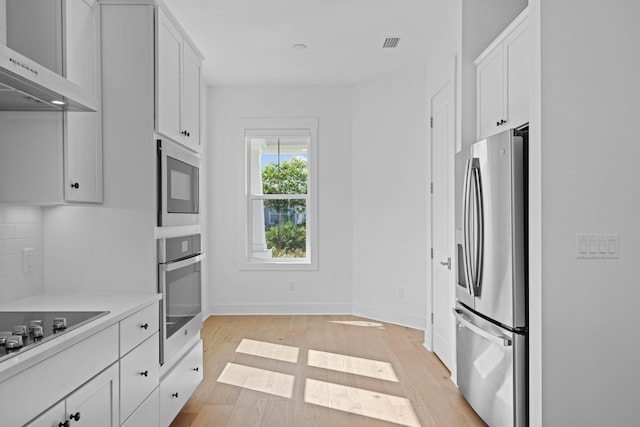 128 Ravine Rd, Watersound, FL 32461 - kitchen with stainless steel appliances, ventilation hood, light wood-style flooring, and white cabinets