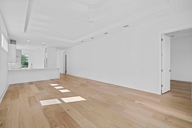 128 Ravine Rd, Watersound, FL 32461 - unfurnished living room with light wood-style flooring, a tray ceiling, a ceiling fan, and recessed lighting